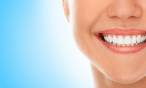 Woman smiling brightly displaying healthy white teeth against a blue background.