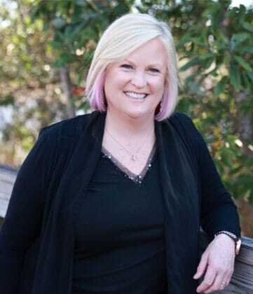 Team member smiling outdoors in professional black attire at Niceville dental practice.