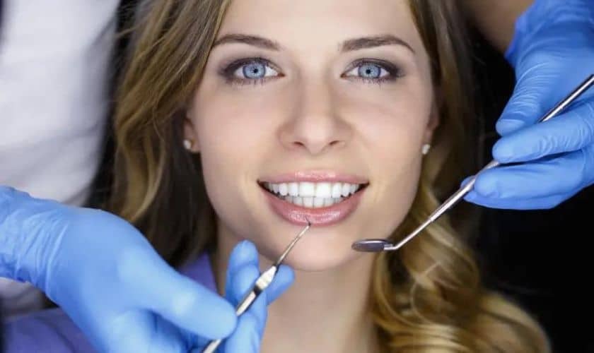 Woman smiling during cosmetic dental examination with dentist tools in Niceville.