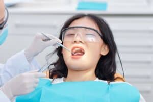 Young patient receiving dental examination with protective eyewear at dental office.
