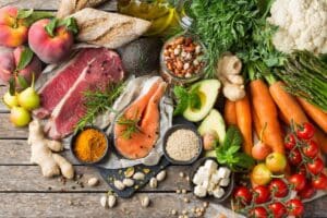 Healthy foods including lean meat, fresh vegetables, fruits, nuts, and whole grains support dental wellness.