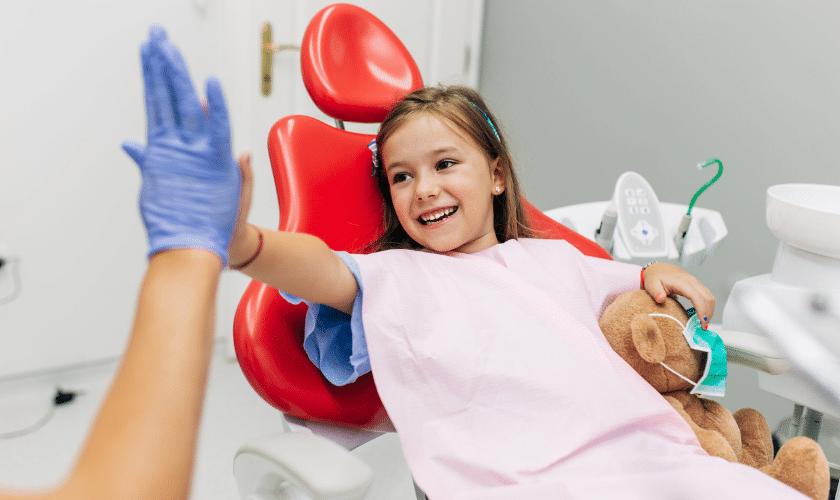 Happy child giving high-five to dentist after successful dental visit in Niceville.