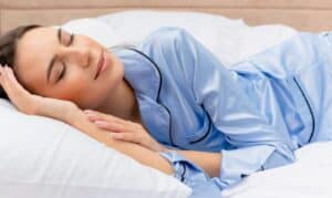 Woman sleeping peacefully on white pillow wearing blue pajamas in Niceville.