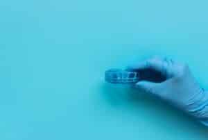 Gloved hand holding a dental model on blue background.