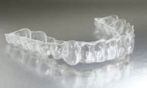 Clear Invisalign retainer tray displayed against a neutral background, showing the transparent dental aligner used for teen.