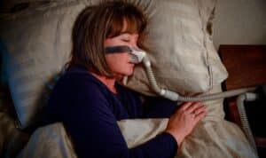 Woman wearing CPAP mask while sleeping to treat sleep apnea.