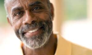 Smiling senior man with healthy white teeth displaying results of cosmetic dentistry.
