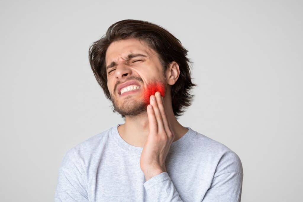 Man experiencing jaw pain after wisdom tooth extraction procedure.