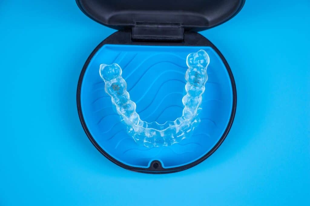 Clear aligner case displaying transparent dental aligners with attachments for front teeth correction.
