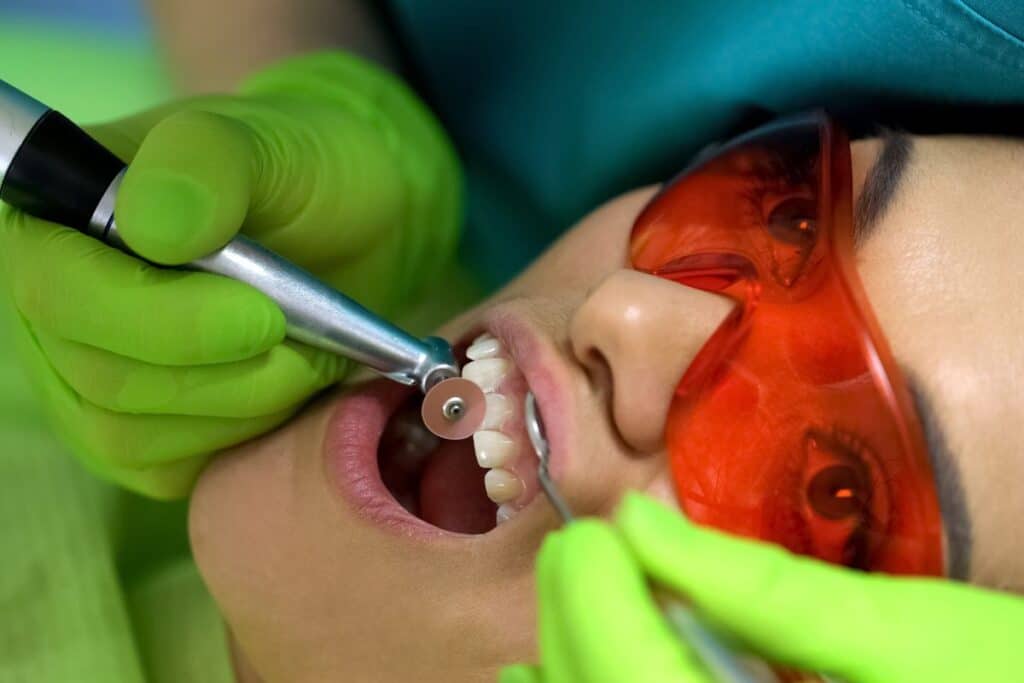 Dentist using dental polishing tool on patient's teeth during cosmetic dental treatment in Niceville.