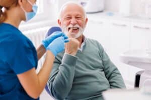 Senior man smiling during dental examination with dentist in Niceville, FL office.
