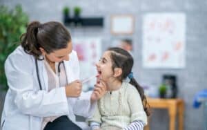 Pediatric dentist examining young girl's teeth during back-to-school dental checkup.