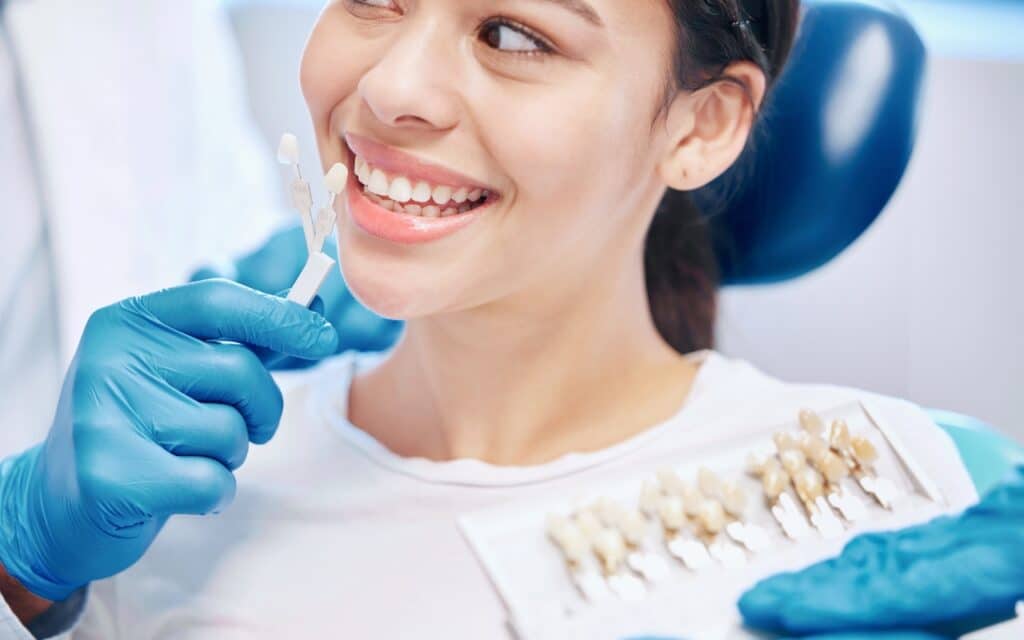 Dentist showing tooth shade guide to smiling patient during cosmetic dental consultation.