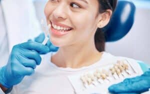 Dentist showing tooth shade guide to smiling patient during cosmetic dental consultation.