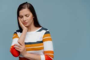 Woman holding her cheek in pain, illustrating dental discomfort management.