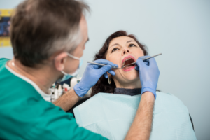 Dentist examining patient's teeth during oral exam in dental office.