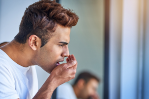 Man with concerned expression touching his face, illustrating bad breath worry and dental concerns.
